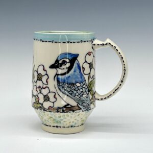 Hand-painted ceramic mug featuring a blue jay among white flowers with pale blue and green accents, view 0