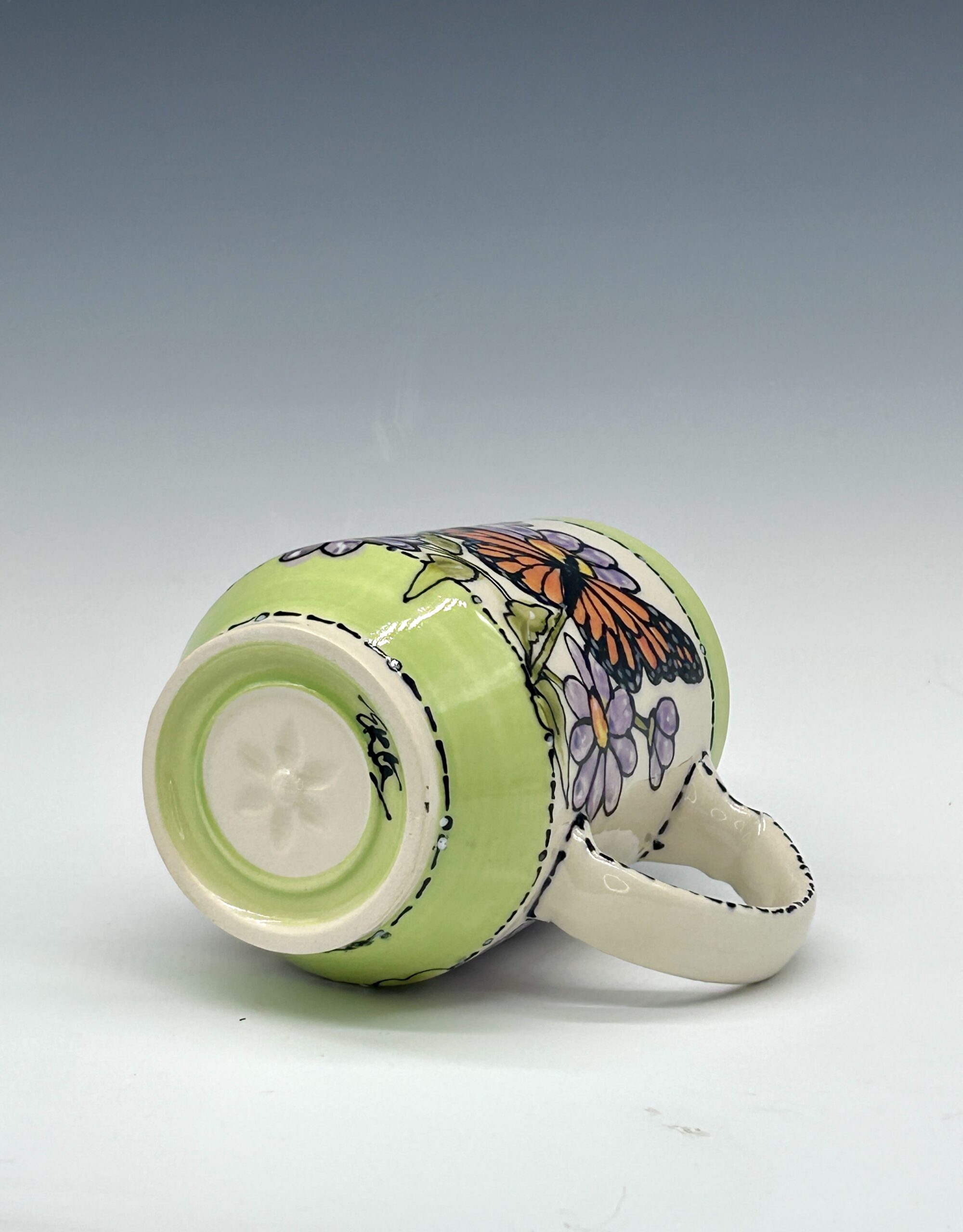 Hand-painted ceramic mug featuring an orange and black butterfly among purple flowers with green accents, view 4