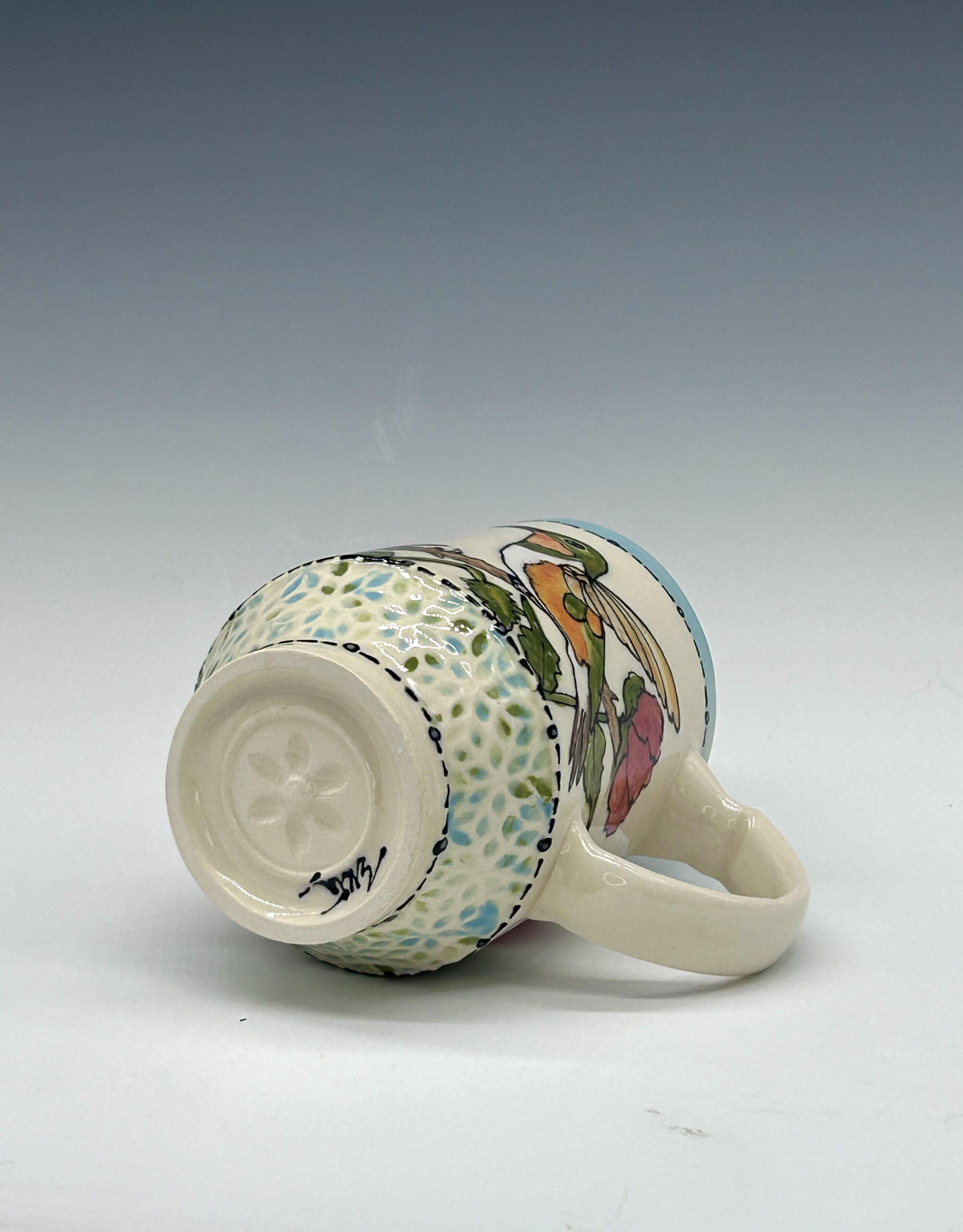 Hand-painted ceramic mug featuring a green and orange hummingbird among pink flowers, view 3