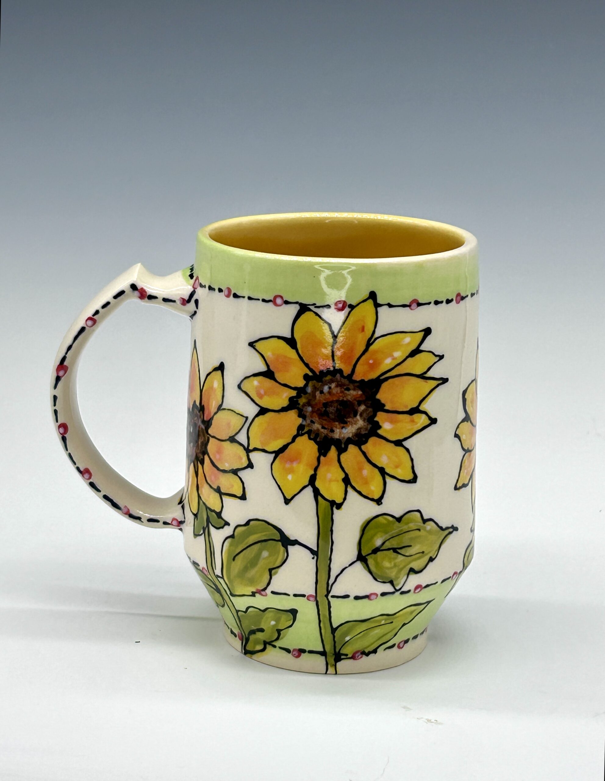 Hand-painted ceramic mug featuring a black, white and red bird among yellow flowers and green leaves, view 1