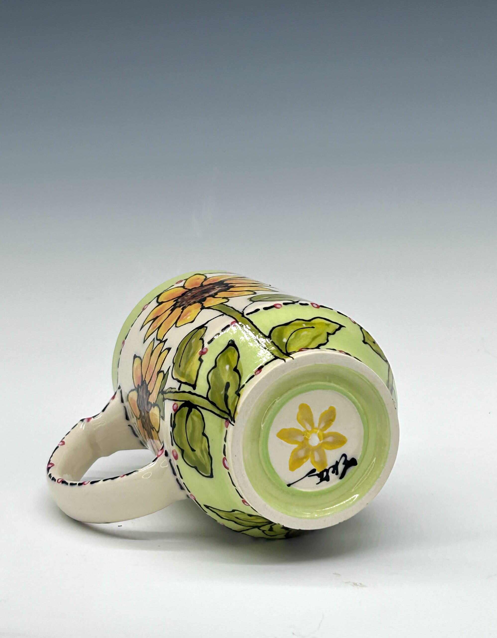 Hand-painted ceramic mug featuring a black, white and red bird among yellow flowers and green leaves, view 3